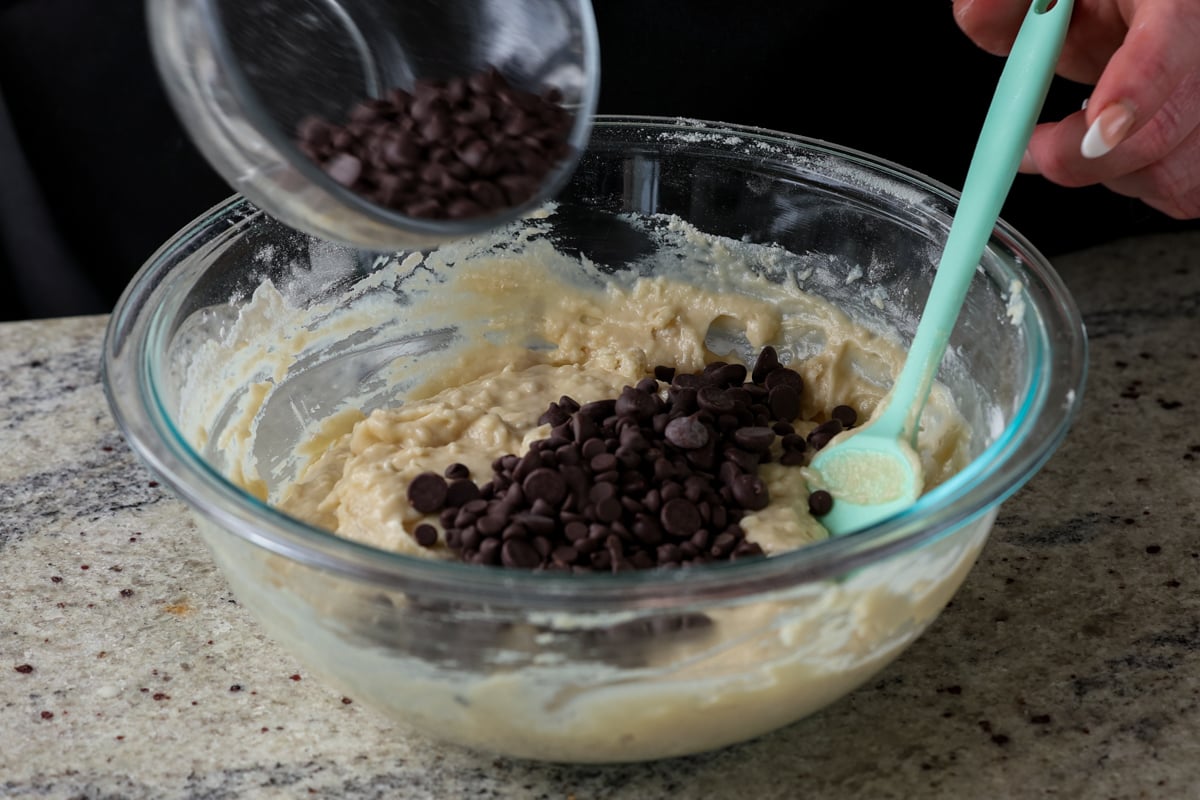 adding chocolate chips to the muffin batter