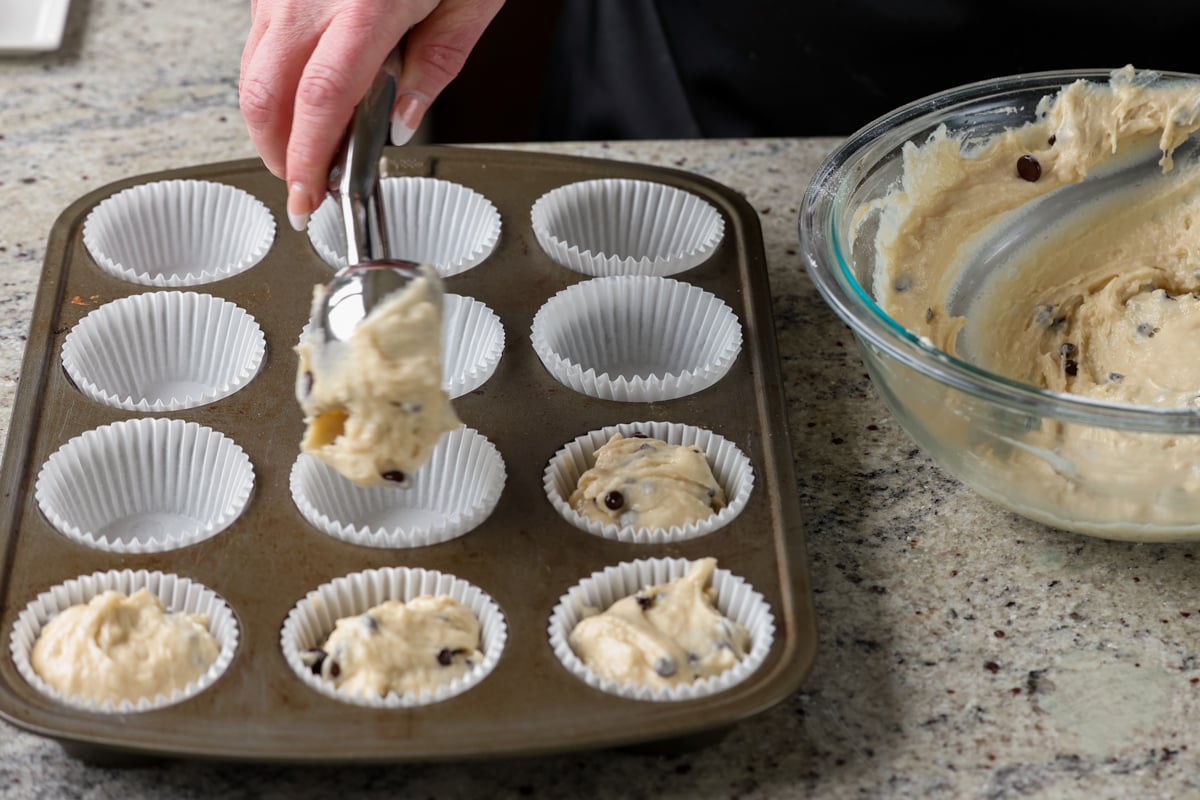 scooping the muffin batter into lined muffin tin