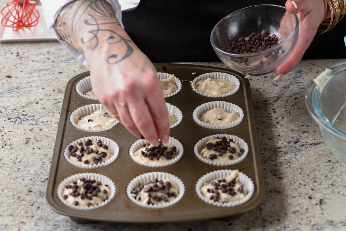 sprinkling chocolate chips onto each muffin