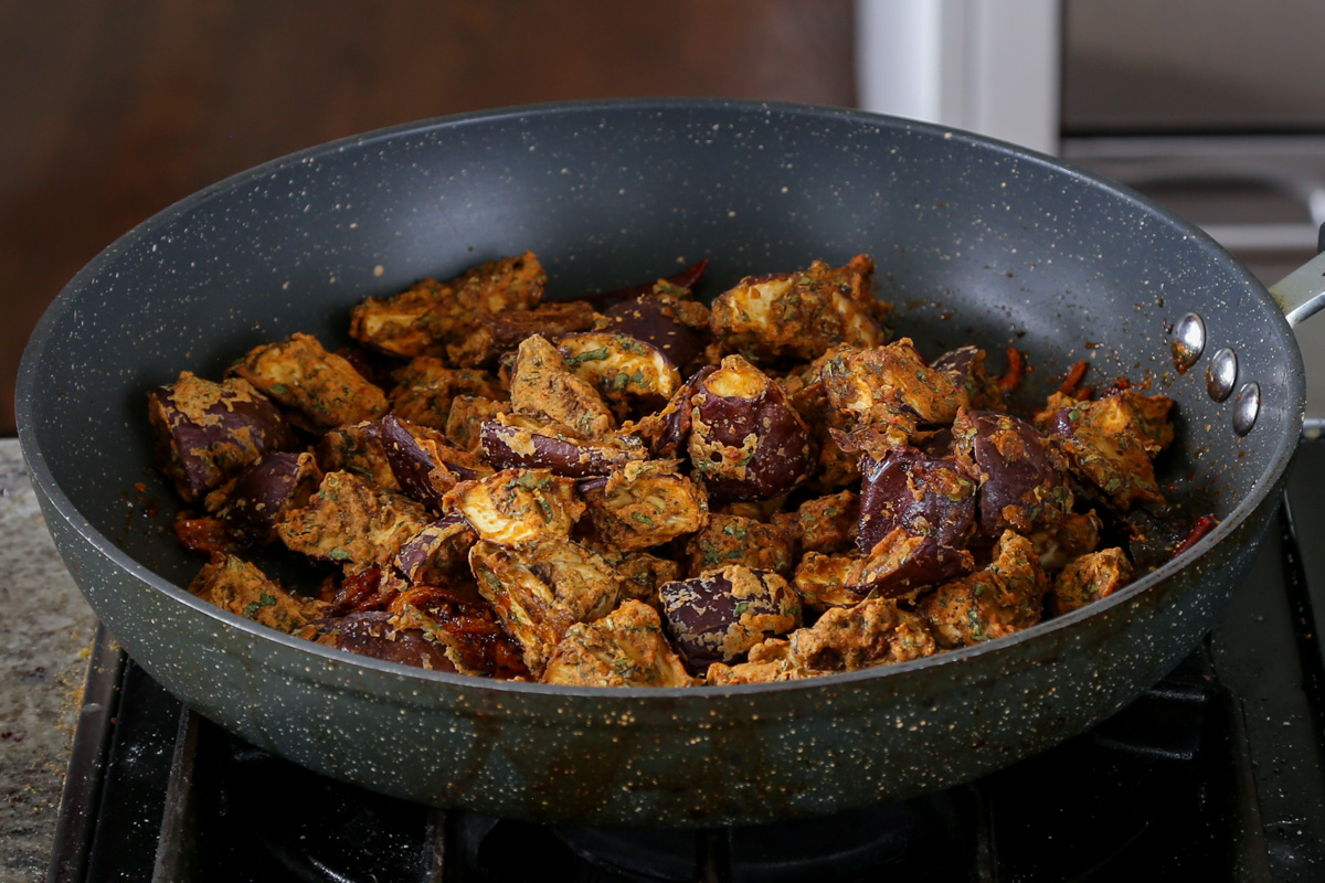 adding eggplant to the pan with the sauce