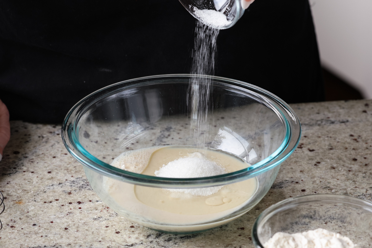 adding sugar to the wet ingredients in a bowl
