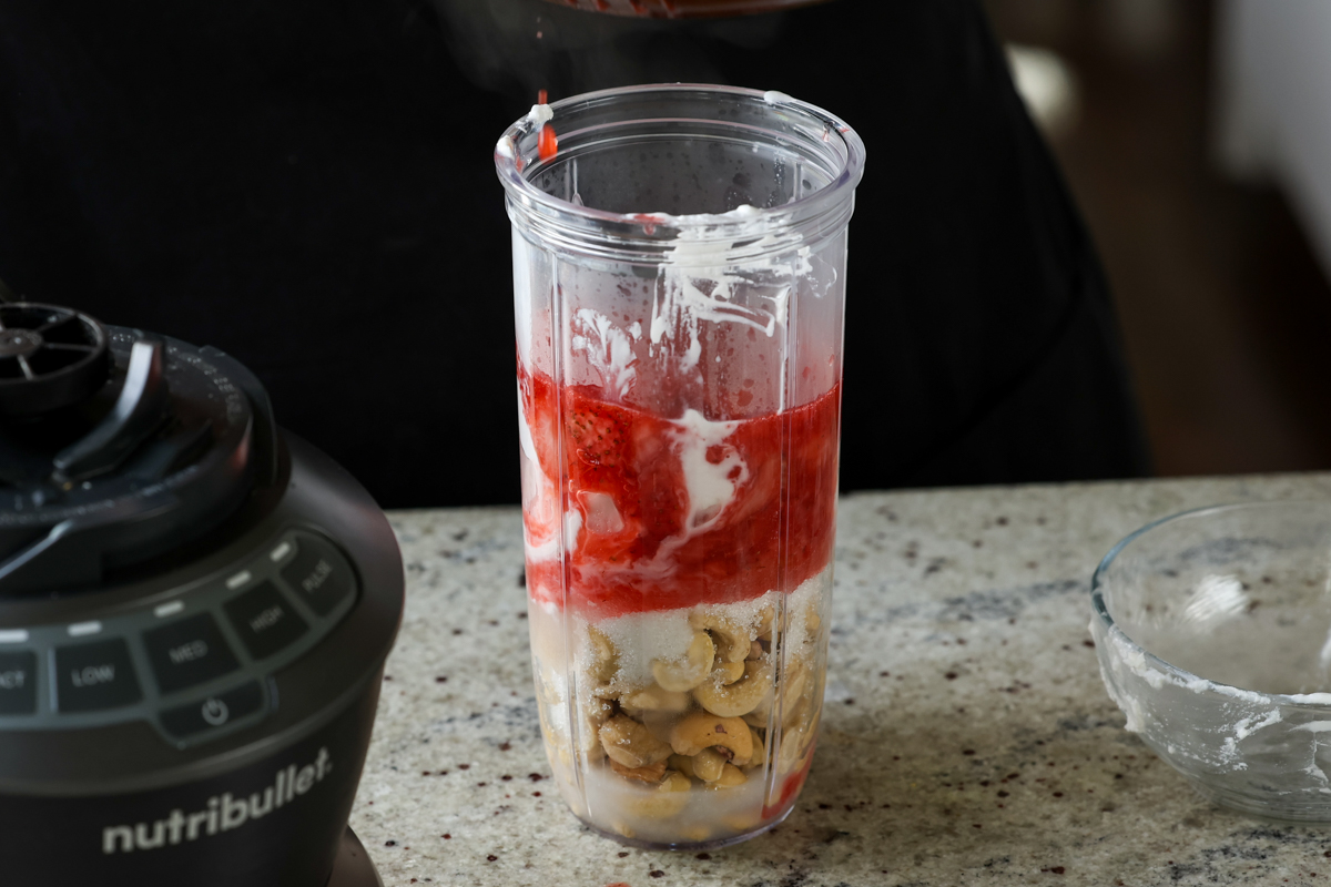 adding strawberry compote to the mousse ingredients in the blender