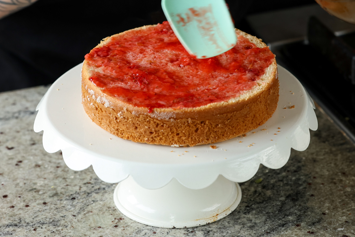 spreading thinned out compote onto the cake