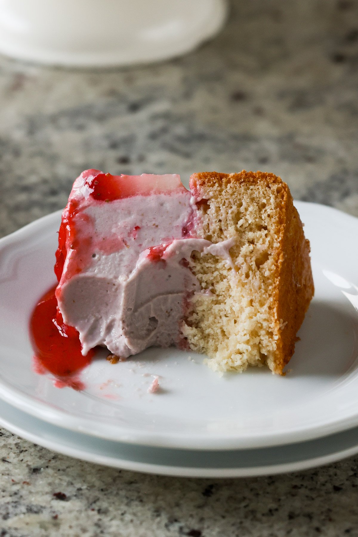 strawberry mousse cake slice on a plate with a bite taken out