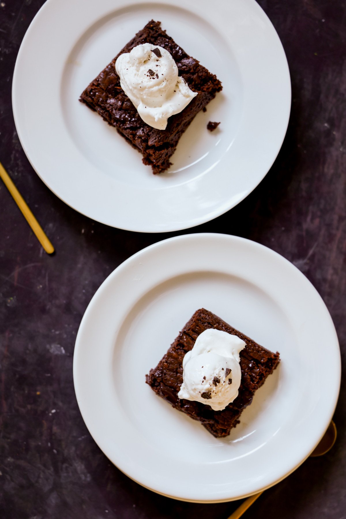 almond butter brownies on plates topped with vegan ice cream