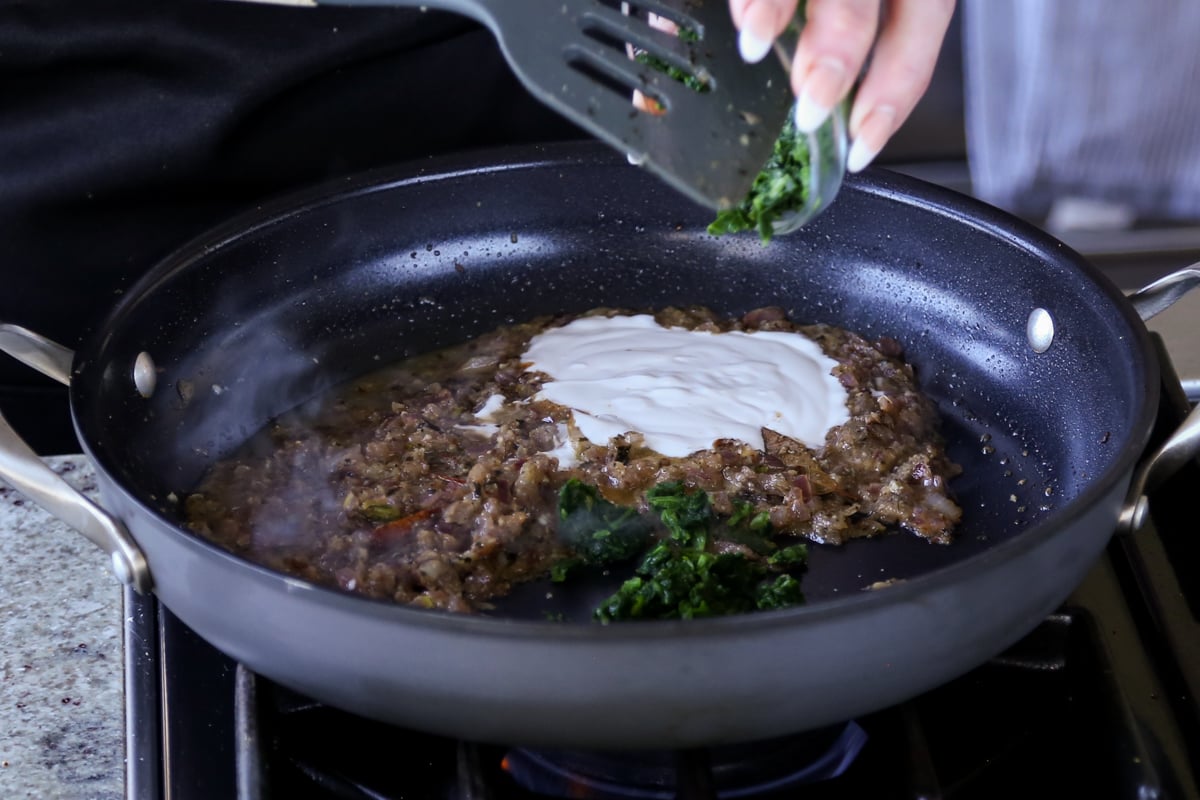adding non-dairy yogurt and spinach to the pan