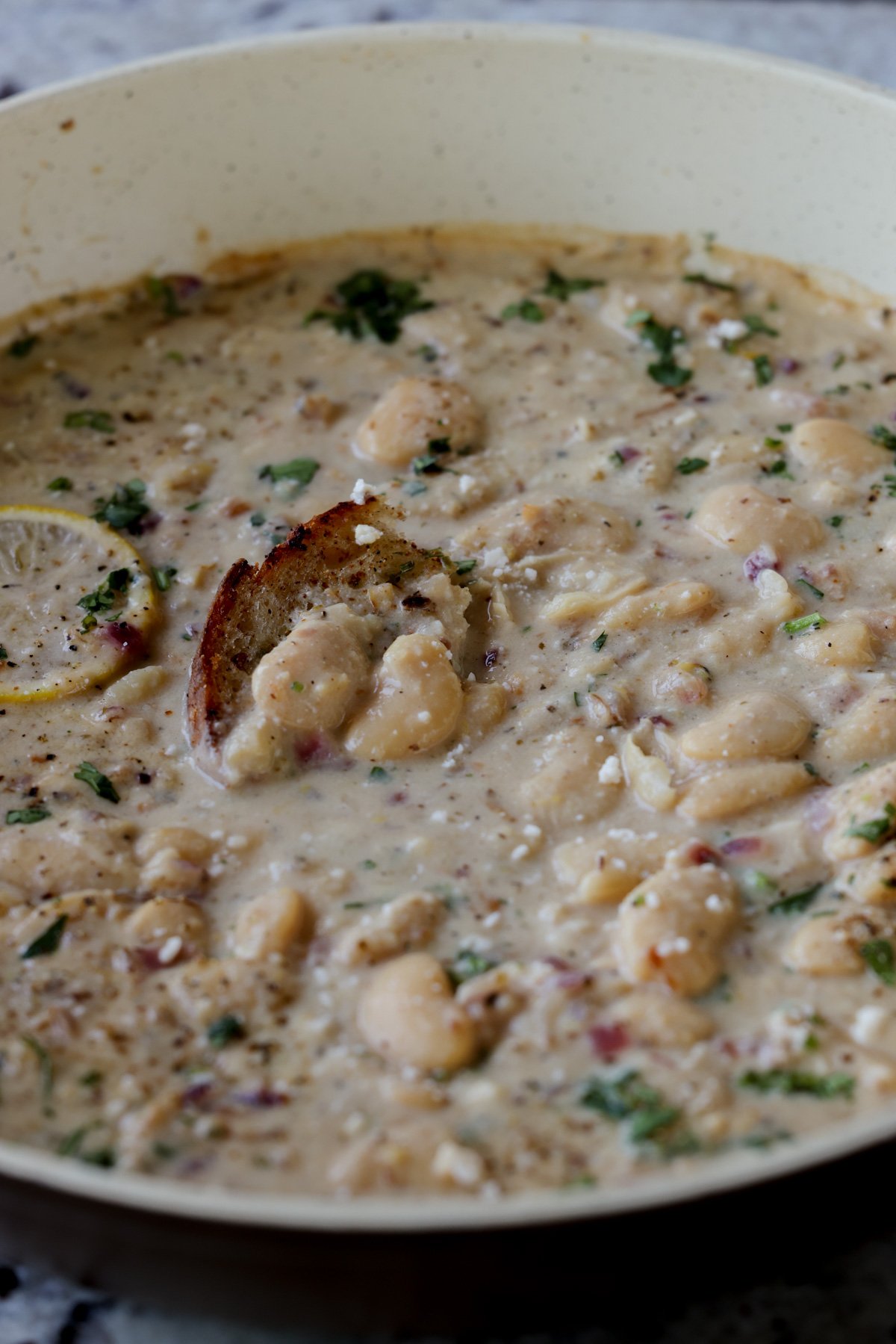 lemon garlic butter beans in a pan with a piece of bread