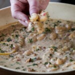 hand scooping up some lemon garlic butter beans on a piece of bread