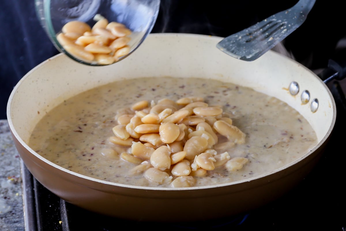 adding the butter beans to the pan of garlic sauce
