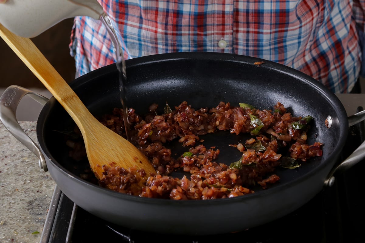 adding water to the onion in the pan