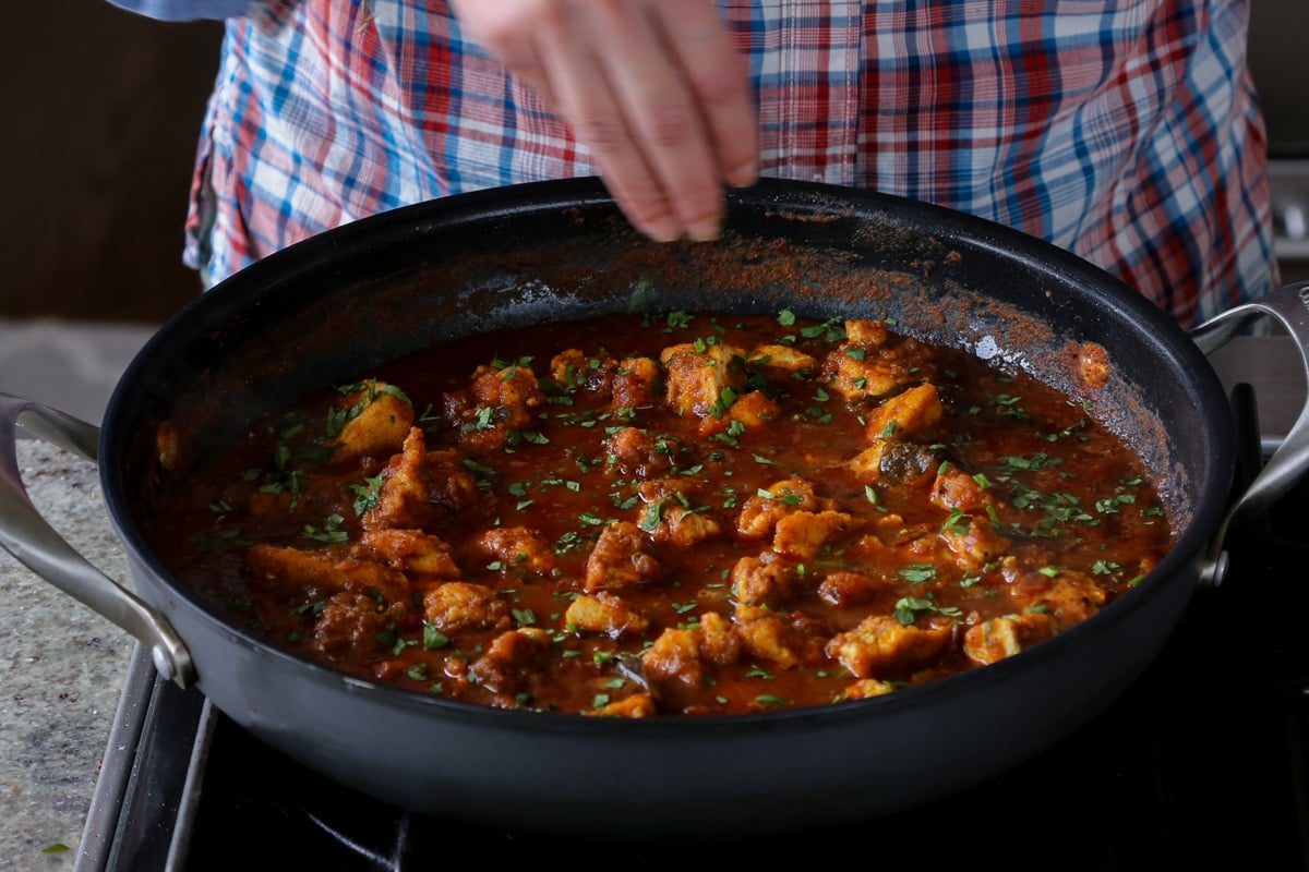garnishing Malvani curry with cilantro after cooking