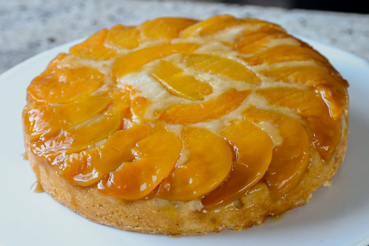 peach upside-down cake on a white cake stand