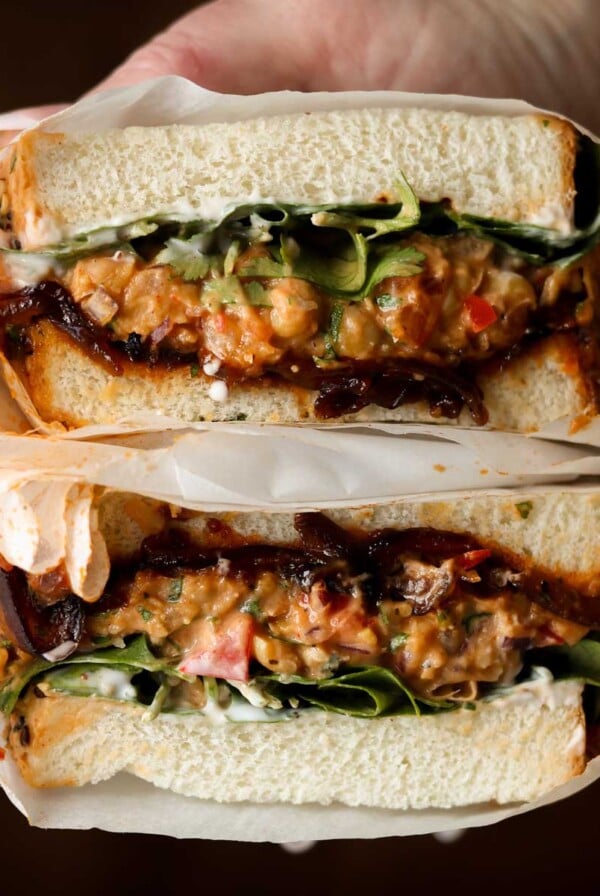 hand holding a gochujang chickpea salad sandwich