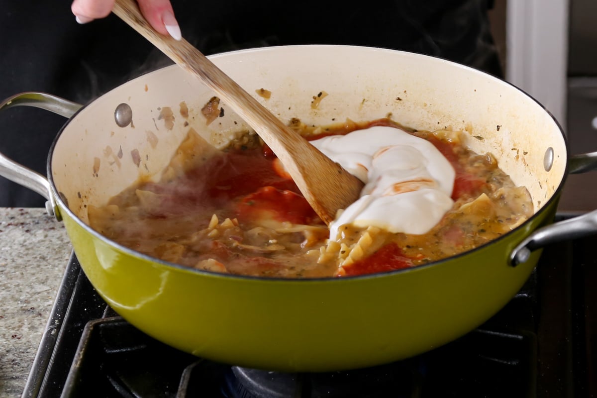 adding tomato puree and cream to the cooked lasagna noodles