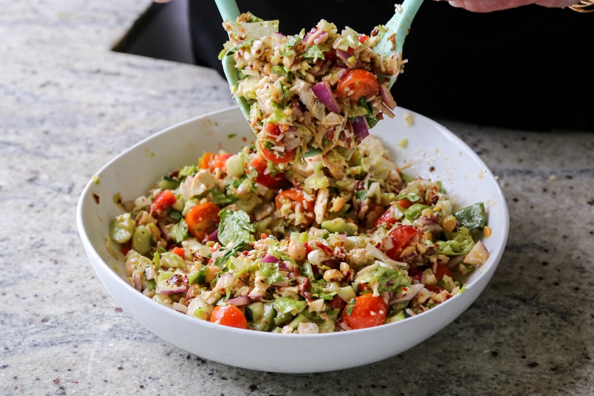 tossing the chopped Italian salad together with the dressing