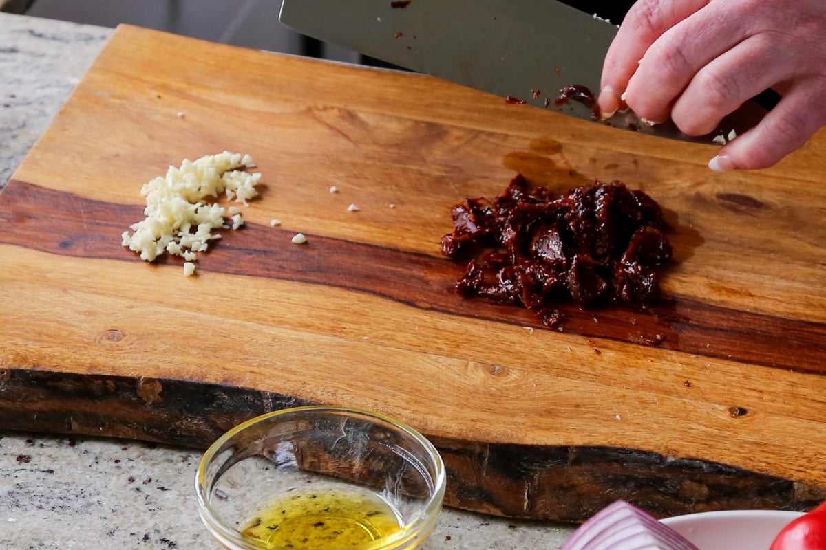 minced garlic and sun dried tomato on a cutting board