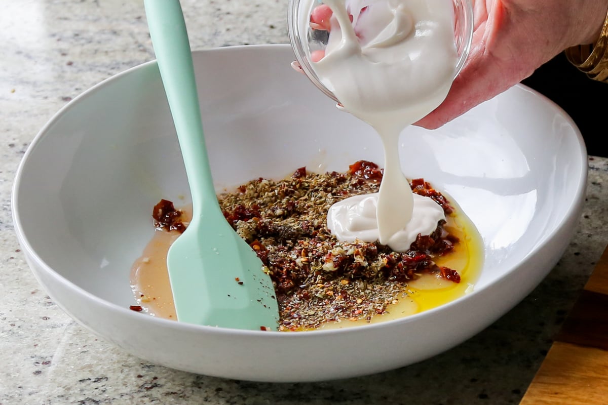 adding Italian dressing ingredients to a bowl