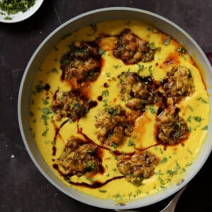 pan of kadhi pakora next to a bowl of cilantro