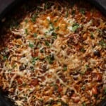 orzo puttanesca in the pan after melting the cheese and topping with herbs and black pepper