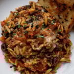 orzo puttanesca on a plate with garlic bread