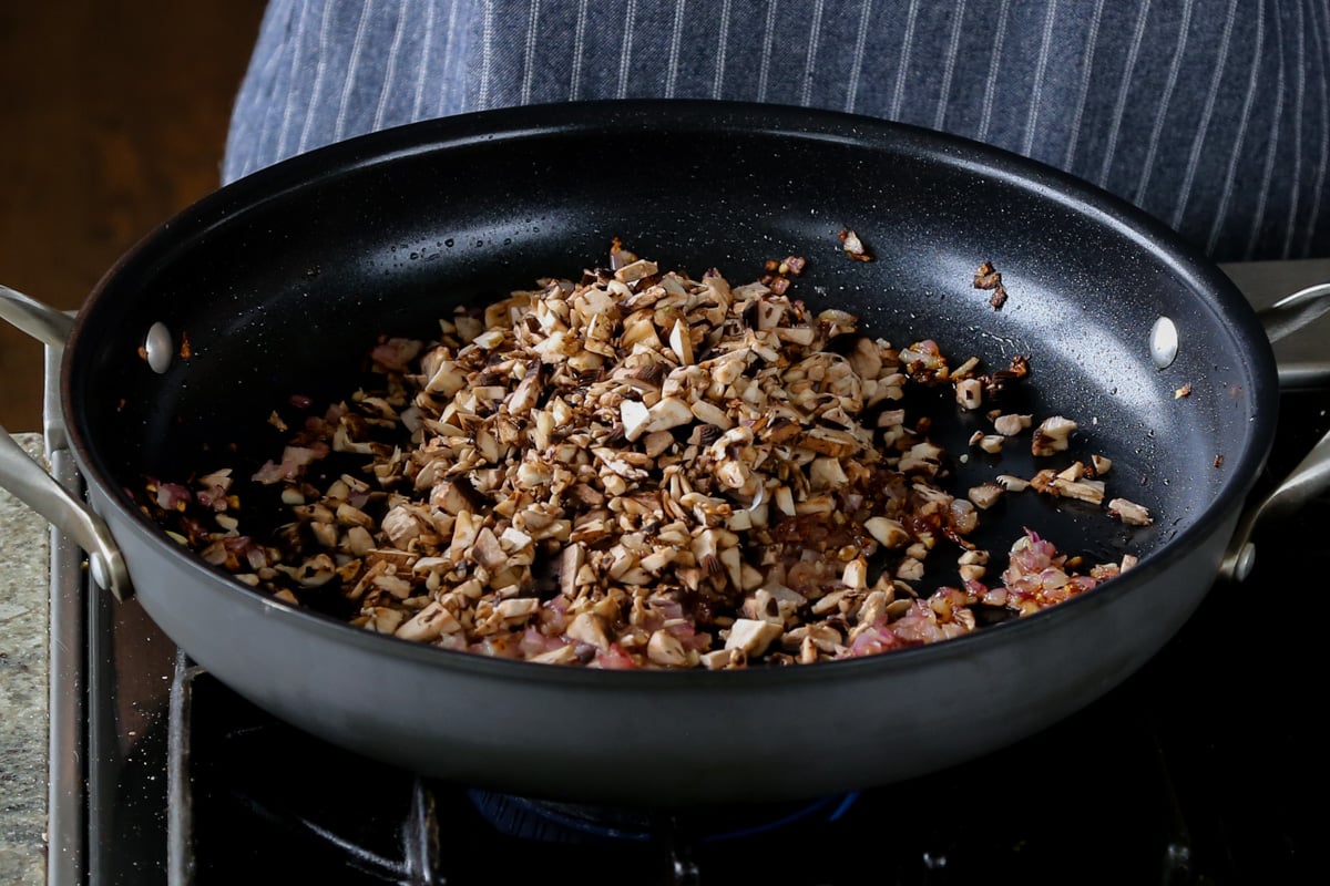 adding mushroom to the pan of aromatics