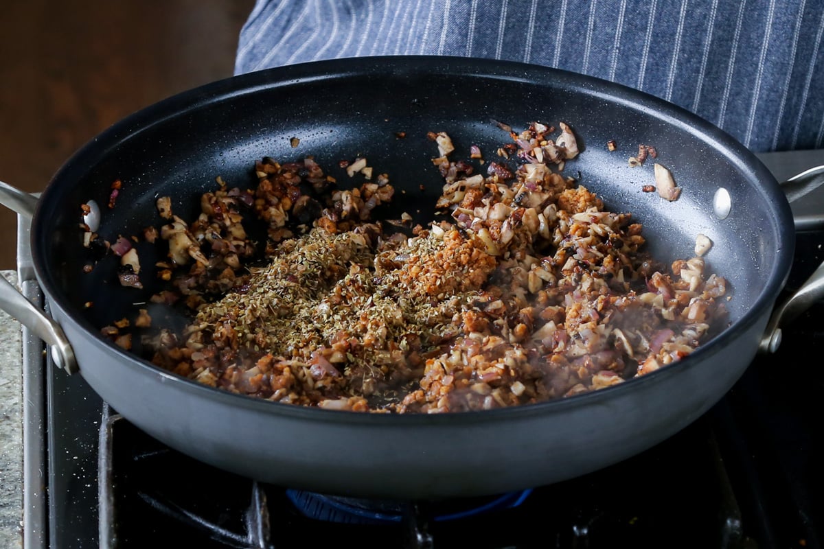 adding dried herbs to the pan