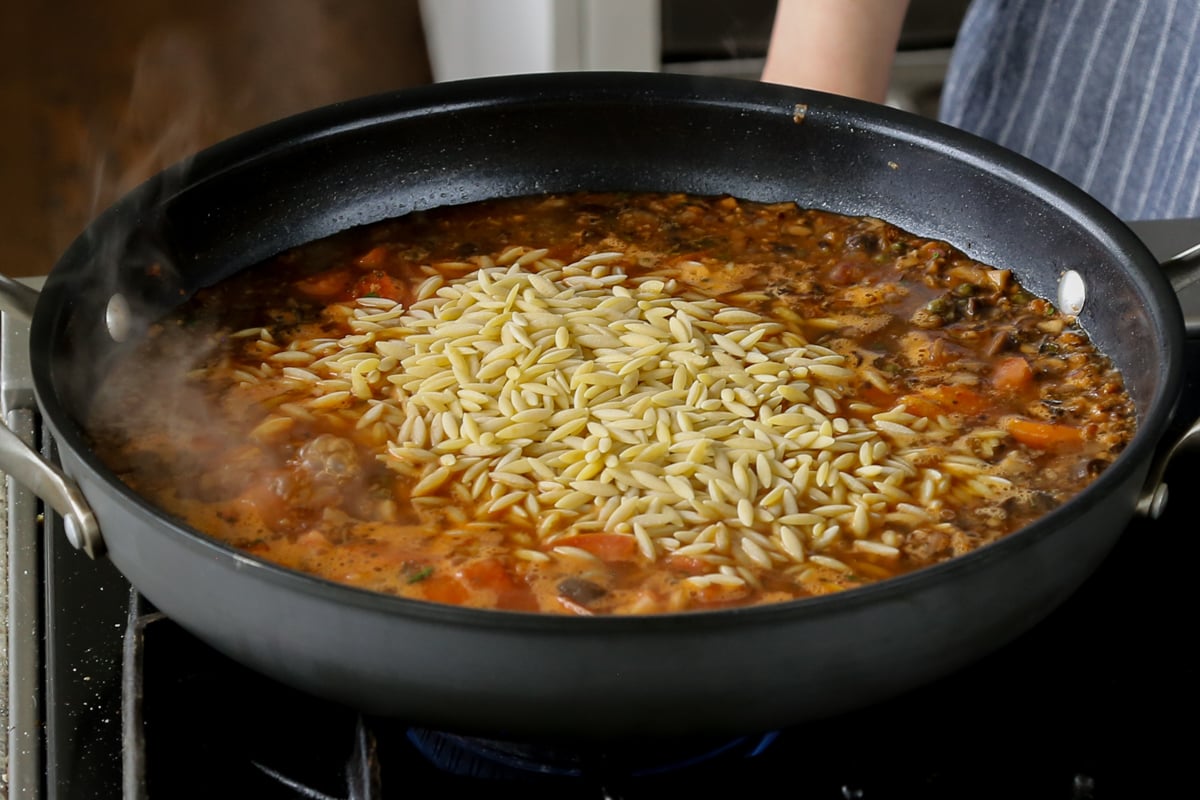 adding orzo to the puttanesca sauce