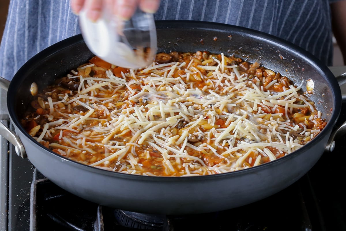 adding vegan cheese shreds to orzo puttanesca after cooking