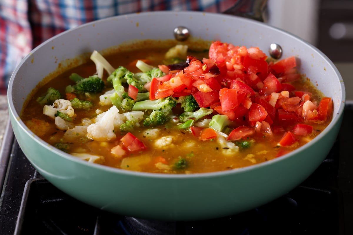 adding tomatoes to the Sindhi kadhi sauce in the pan