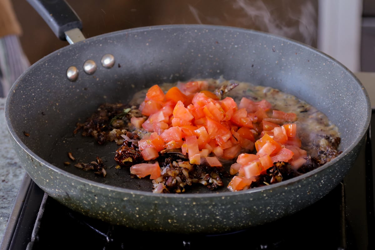 adding tomato to the pan