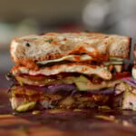 grilled veggie sandwich sliced in half on the cutting board