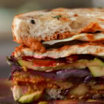 close-up of grilled veggie sandwich sliced in half on the cutting board
