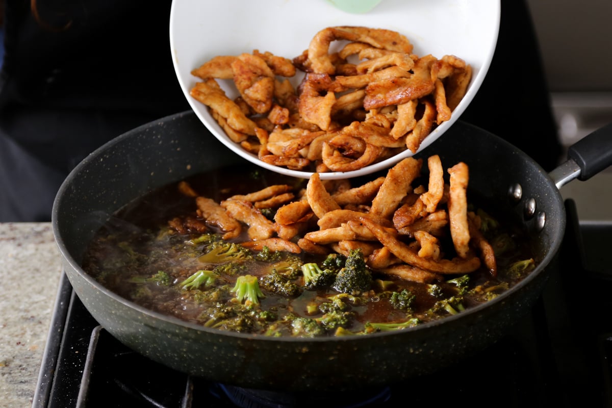 adding soy curls to the broccoli and sauce in the pan