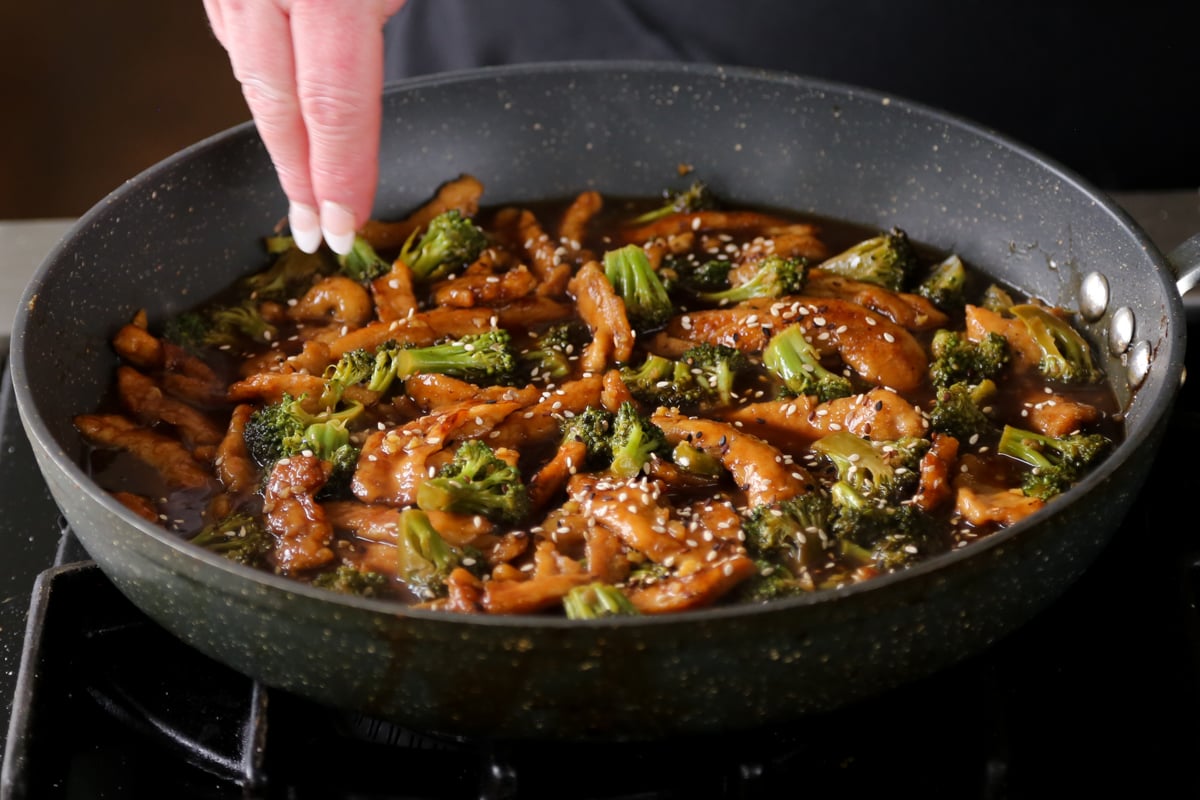 adding garnishes to the cooked vegan beef with broccoli