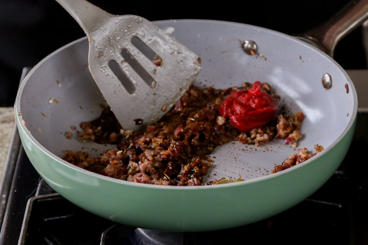 adding tomato paste to the pan