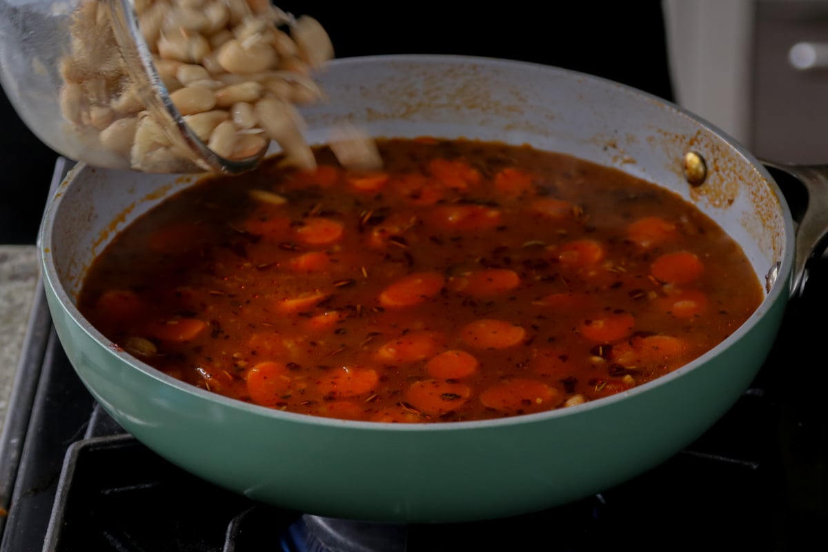 adding white beans to the pan