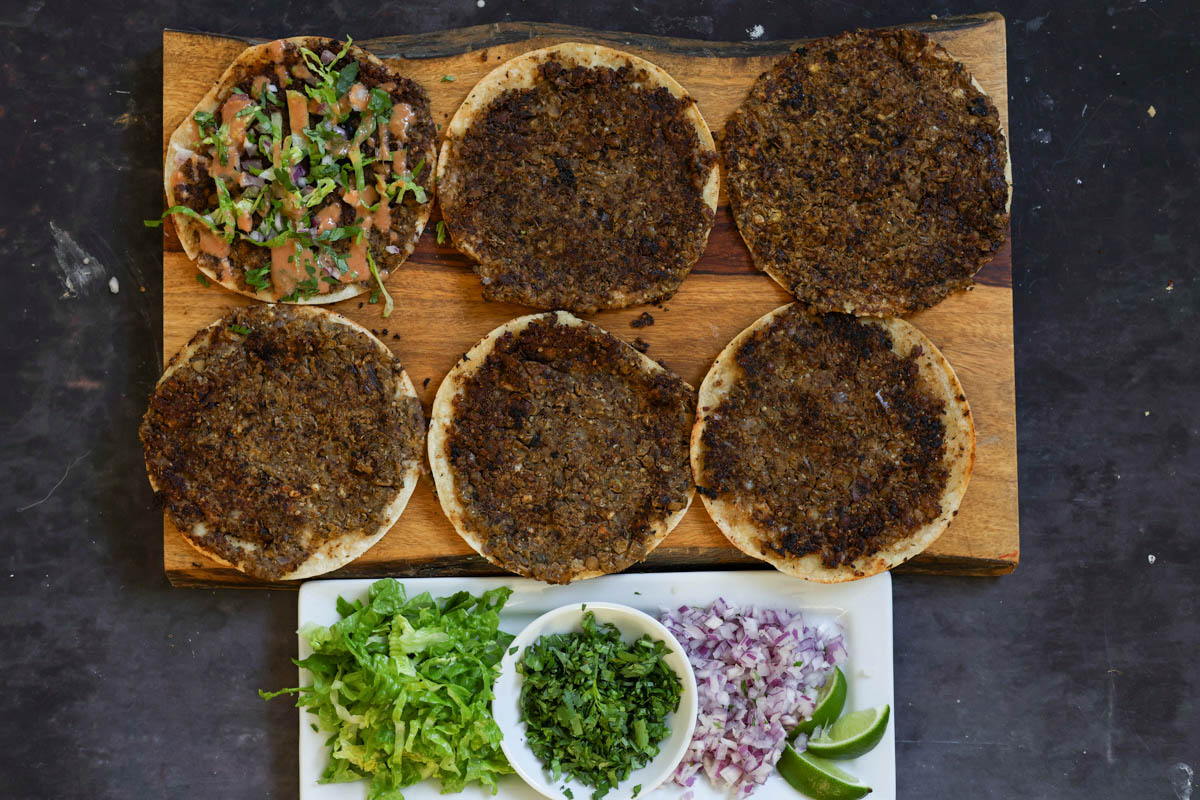 adding the toppings to the smashed tacos