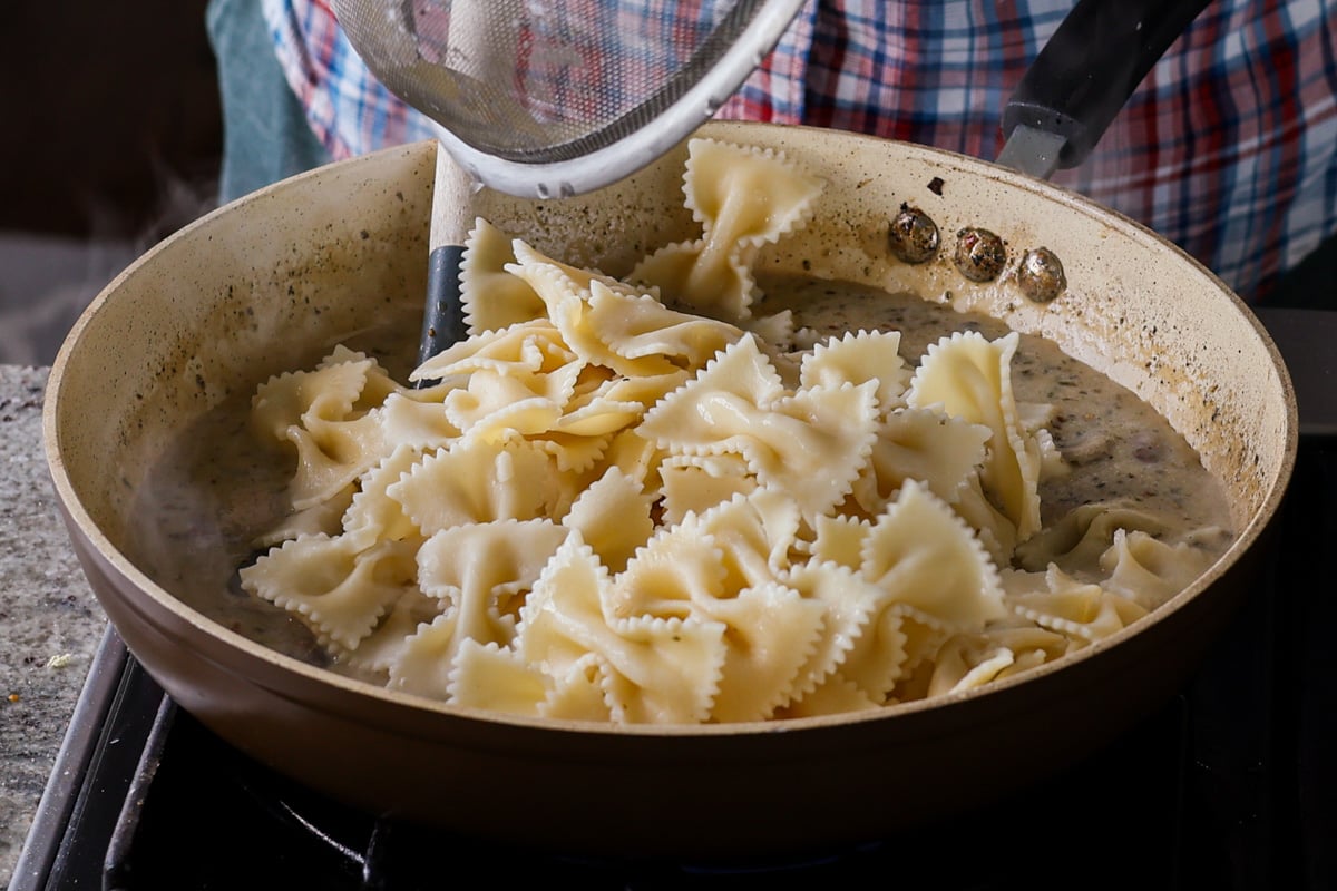 adding farfalle pasta to the pan