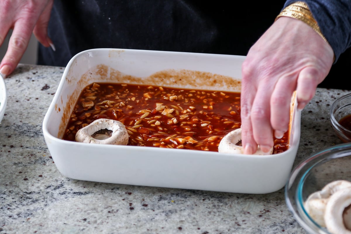 adding mushrooms to the pan of pasta