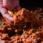 hand scooping up chicken angara with a piece of naan