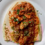 flatbread with chicken angara on top on a plate
