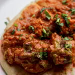 close-up of flatbread with chicken angara on top on a plate