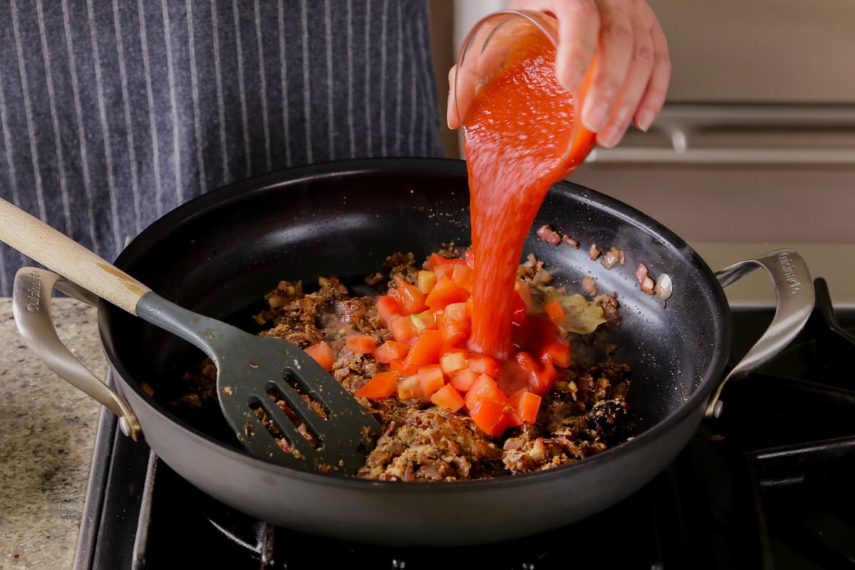 adding tomato puree to the pan