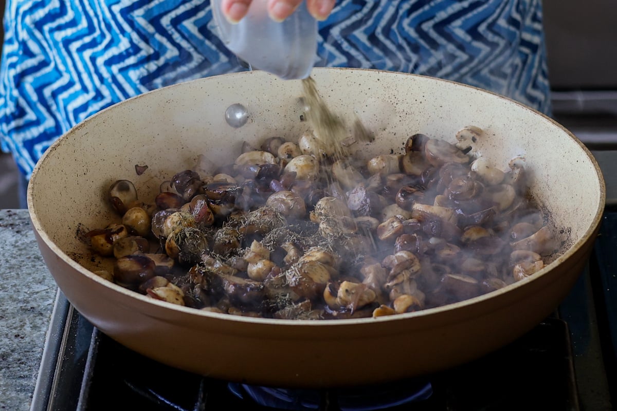 adding dried thyme to the mushrooms