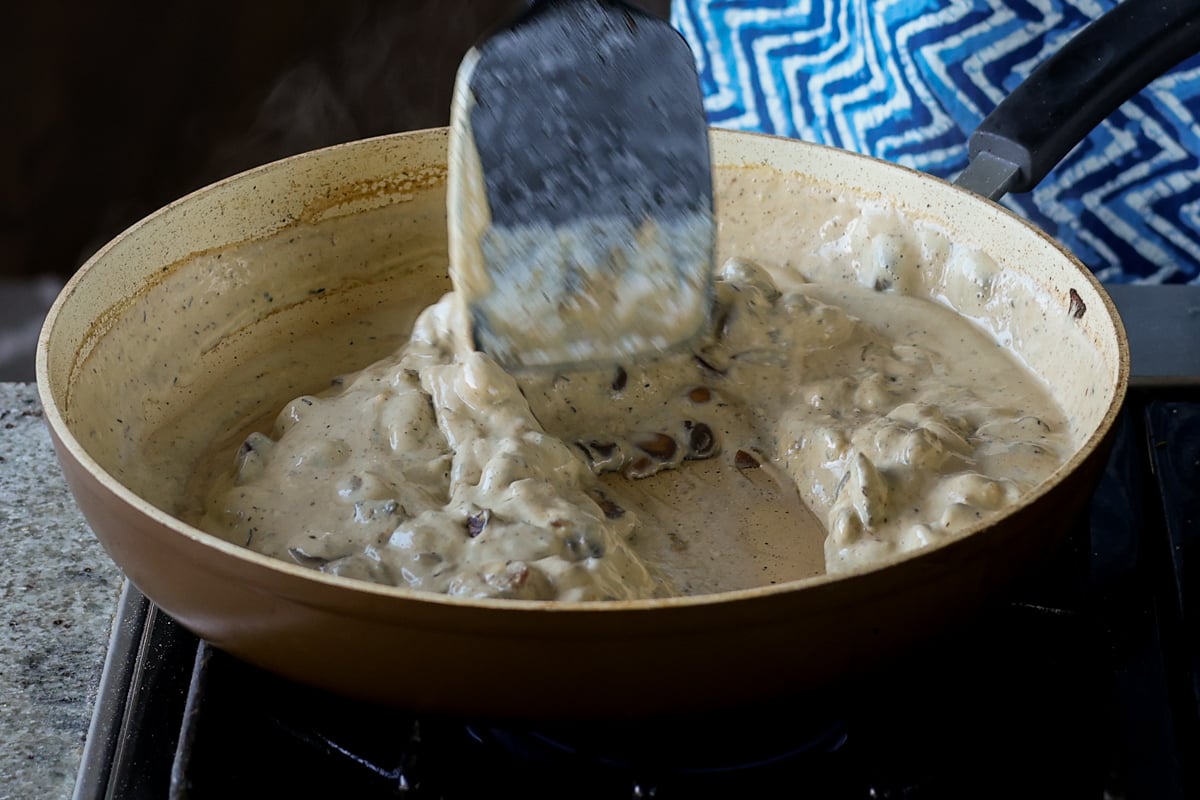 stirring cream sauce into the mushrooms