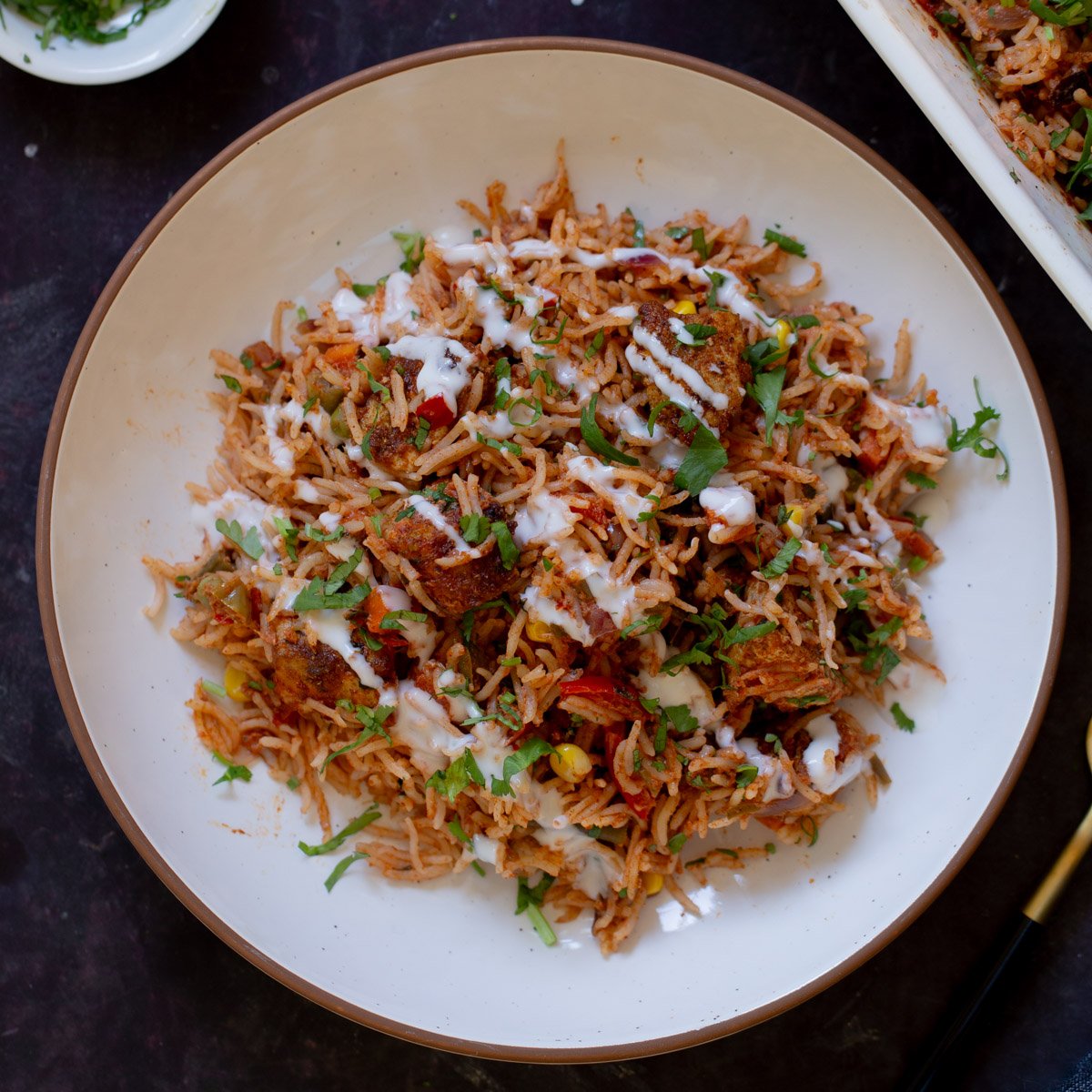 plate of tikka masala rice topped with yogurt and cilantro