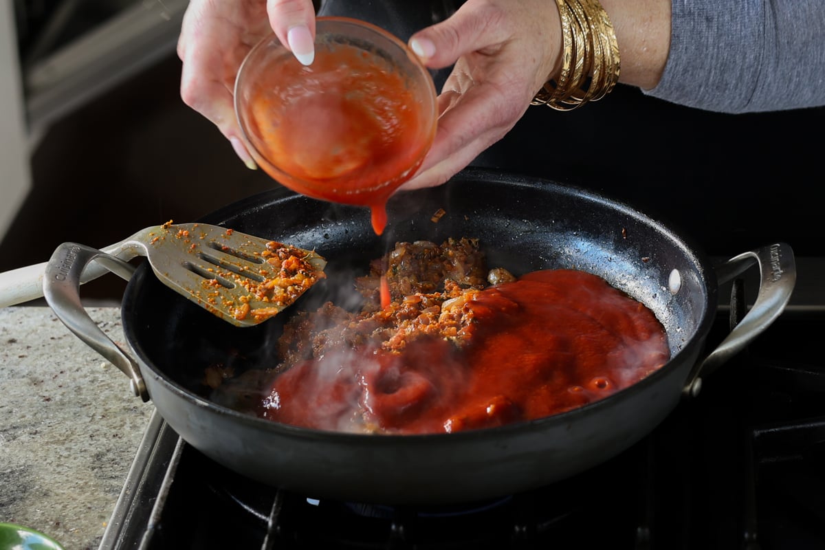 adding tomato puree to the sauce