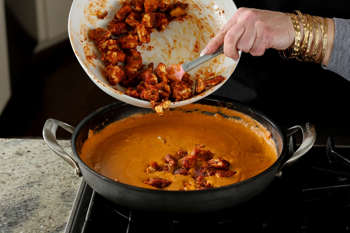 adding tofu to the butter chicken sauce