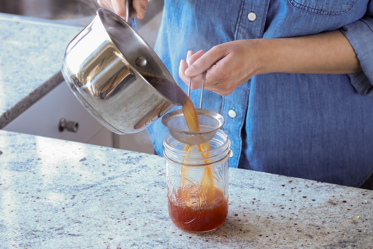 straining chai concentrate into the jar
