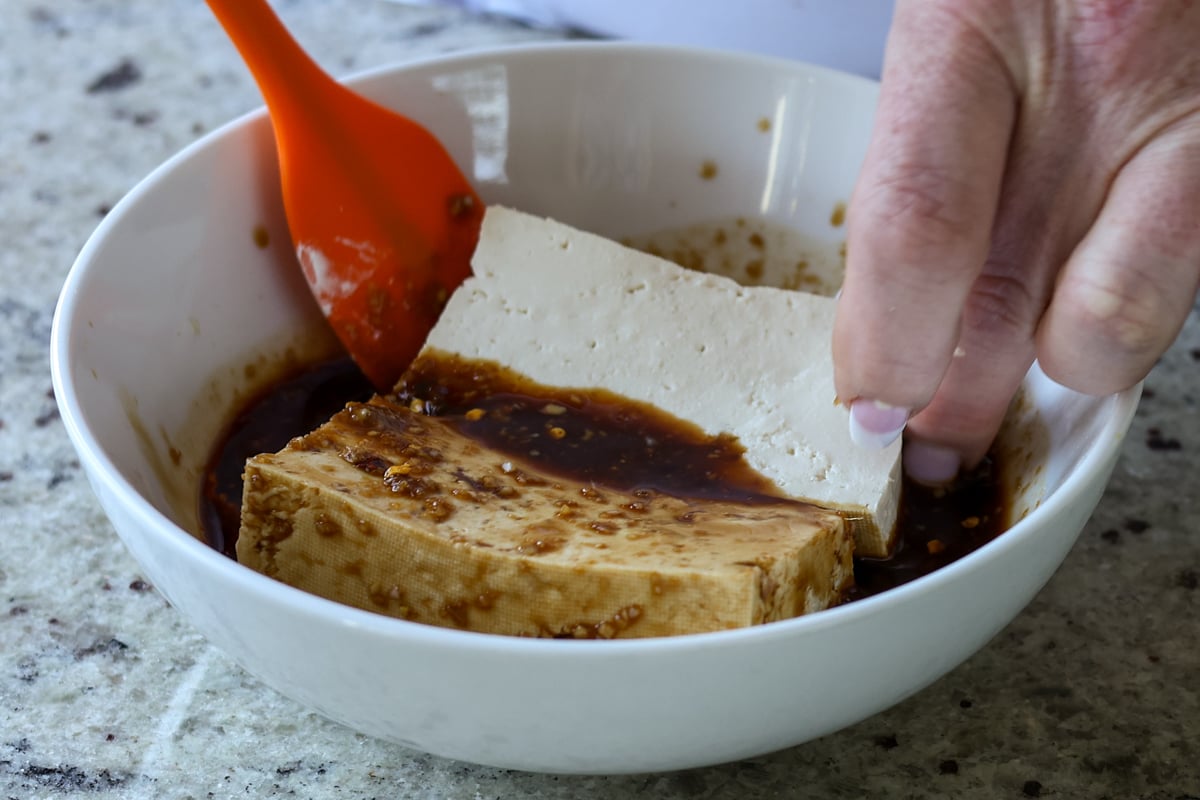 adding tofu slabs to the teriyaki sauce
